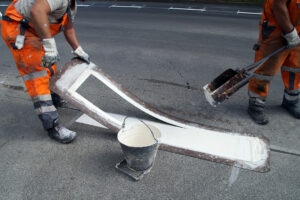 A closeup shot of a worker printing street lines for driving on the ground
