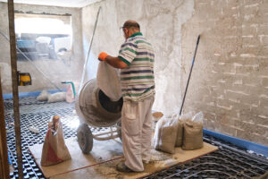 Construction worker loading a sandbag into the concrete mixer. Builder adding sand to the concrete mixer during concrete cement solution mortar preparation.