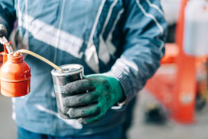 Professional mechanic in uniform holding an oil filter for an internal combustion engine. Service station worker.