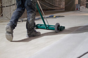The worker is skillfully using a mechanical brush to clean and polish the surface of the floor, ensuring that it remains in top condition.